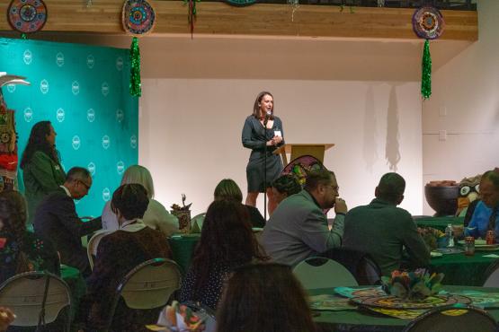 Woman speaks to seated crowd from podium