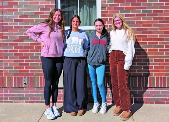 Four female students standing outside of a brick building