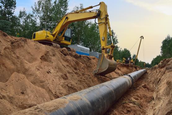  An excavator digs up a road to replace a pipe. 
