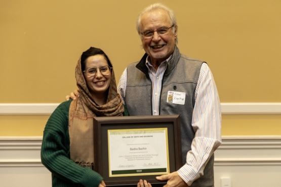 Badra Bashir and John Kopchick hold the award
