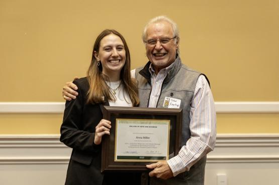John Kopchick and Anna Miller hold the award