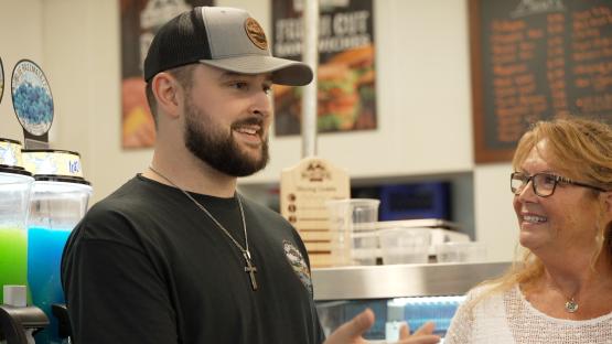 An individual from the High Street Deli speaks to a representative from the Small Business Development Center