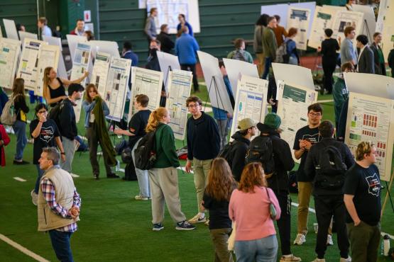 OHIO students stand  in front of their research posters and discuss their work at the Student Research Expo in Walter Fieldhouse