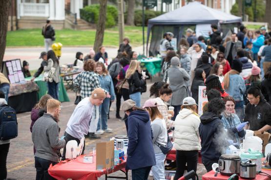The streets is filled with people walking to and from booths at the International Street Fair. The College Green is in the background.