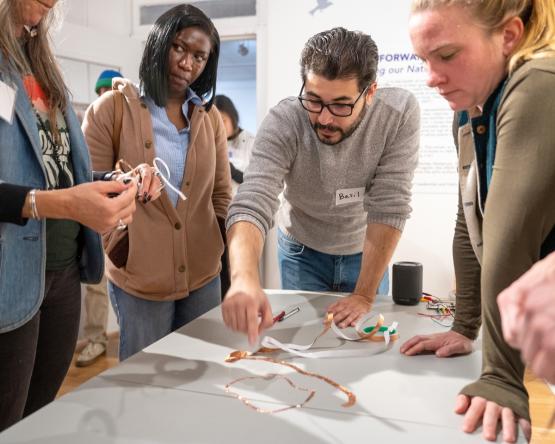 OHIO faculty and students examine an object on a table and talk about it. 
