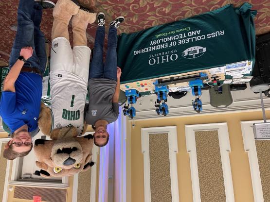 Brandon Petrie standing with Rufus at an outreach event with robots.