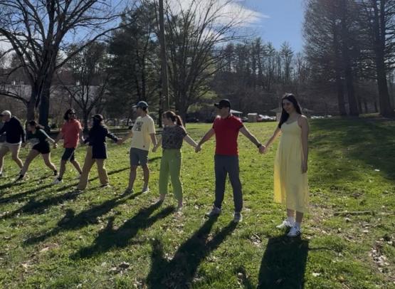 OHIO students hold hands while standing in a line outside as part of a game during the Nowruz celebration.