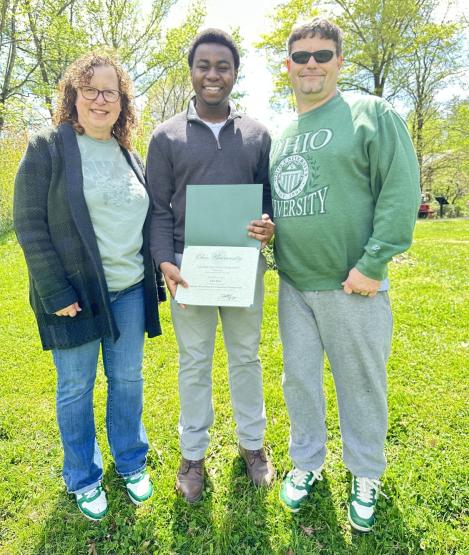 Tracy Watson and Corey Boby stand with John Iluno, who is holding an award certificate