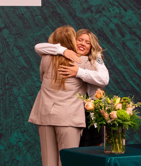 An OHIO student receives a hug from a speaker on the stage during the ceremony