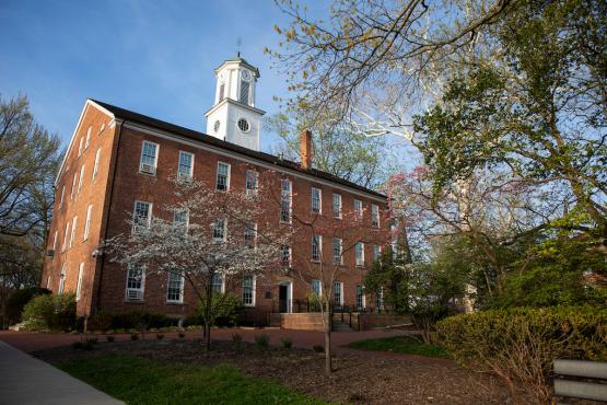 Cutler Hall is shown surrounded by colorful trees on a sunny day in the spring