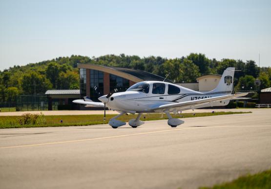 A plane with an OHIO logo on it is shown flying just above the aiport runway, and the Gordon K. Bush Airport is shown in the background