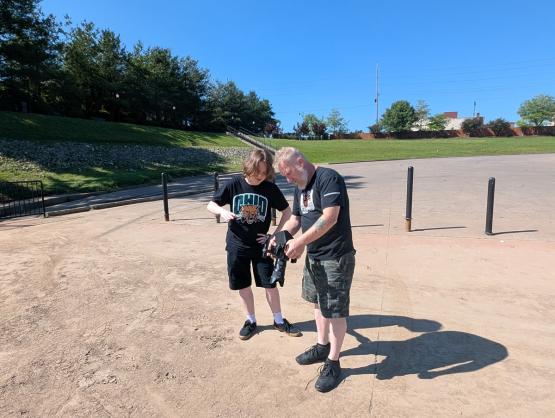 An OHIO faculty member and a student look over a camera while outside working on a documentary film project