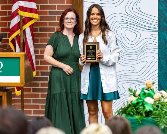 Ellen Plank holds her award while staning next to Dr. Theiss during the Pinning Ceremony