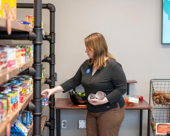 A Cats Cupboard employee puts food items on a shelf at the food pantry