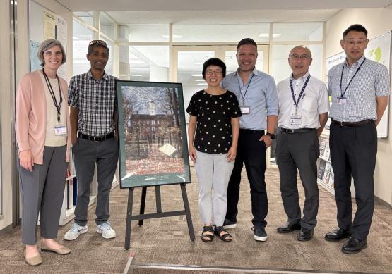 OHIO and Chubu University representatives stand together next to artwork that features OHIO's Cutler Hall