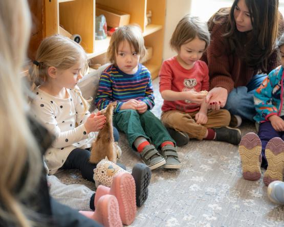 Children at the Child Development Center sit together while an Ohio University student sits with them
