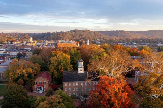 Cutler Hall is shown surrounded by colorful trees, with hilldsides in the background in this aerial image