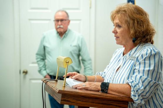 A mayor speaks at the podium while another individual looks on