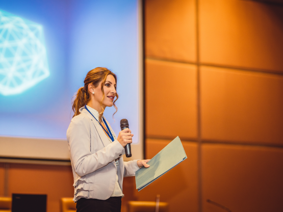 woman standing in front of room with a microphone