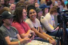 People sit in a row as part of an audience for the Music Industry Summit. One girl smiles at the camera
