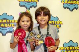 Two children pose for a picture holding award ribbons