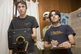 Three students stand behind a camera, circa 2008