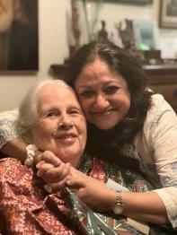 Two women pose for the camera, embracing and smiling