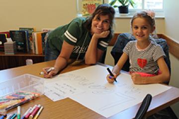 A participant in the Patton College Math and Literacy Camp works with a staff member to create signage
