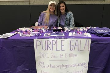 Two nursing students pose at a table promoting the Purple Gala.