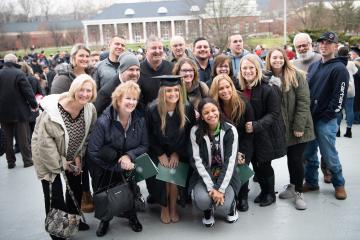 Graduate poses with her family and friends after Fall Commencement.