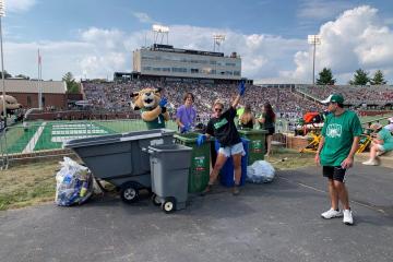  Rufus with Campus Recycling Team Member, Carly Cunningham and a student Rufus Green Team Volunteer gathering and preparing to sort recyclables inside Peden stadium.
