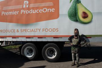 Roshelle Pate poses for a photo in front of one of the trucks that delivered palettes of fresh food for free drive-through grocery distributions that were held in Athens in October. 