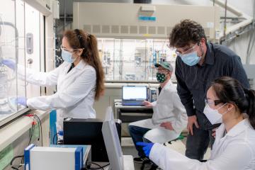Marc Singer and three students wearing masks work in the lab facility