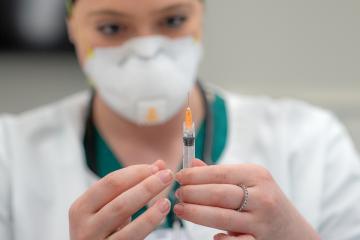 A masked person handles a vial of something