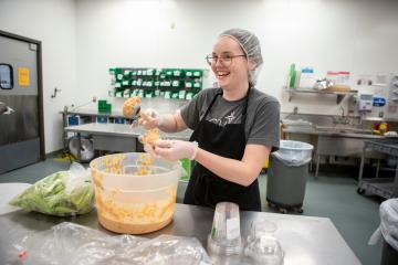 An OHIO student laughs while working in the kitchen of the Central Foods Facility