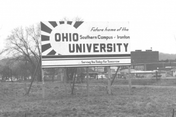 A black and white photo of an old billboard sign that reads 