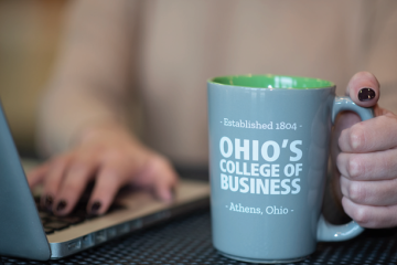 Mug that says "Ohio's College of Business" next to a laptop