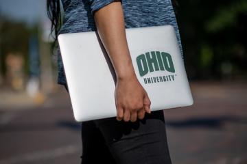 A phot of an Ohio University student carrying a computer