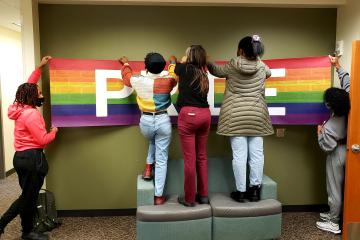 Students hang a sign in the new LBGT Center