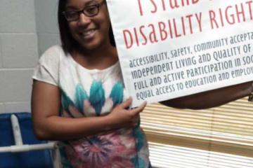 Tyaira Williams holding a sign that says "I stand for disability rights"