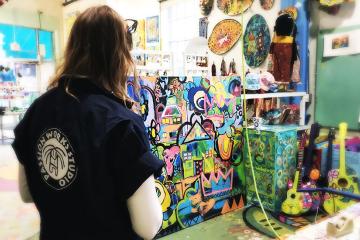 Passion Works Studio artist-in-residence Wendy Minor Viny is seen with “House of Love,” a painting commissioned by Ohio University’s Division of Student Affairs in honor of Dr. Jenny Hall-Jones.