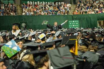 A student celebrates at undergraduate commencement at the Convocation Center in Athens.