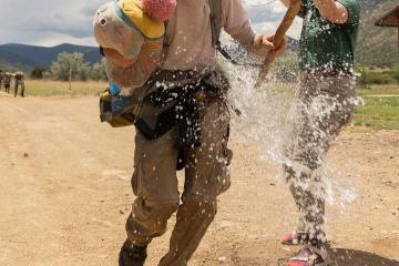 Andrew Wettemann gets water dumped on him by his sister, Sarah Wettemann, as he returns from his Rayado Trek on July 9, 2022 in Cimarron N.M.