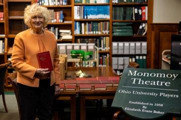 Anne Baker poses with her father's journal collection at Ohio University