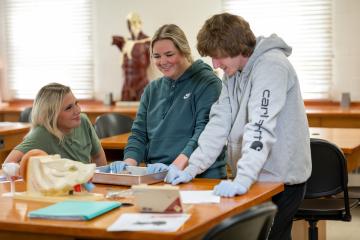 three students in a dissection lab