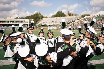 Members of the Marching 110 form a giant hug and cheer during an Ohio University football game