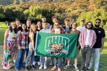 Students in the OHIO-in-LA program pose with an OHIO flag in front of the Hollywood sign in Los Angeles