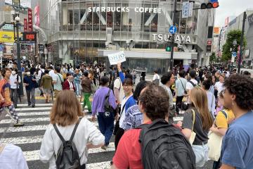 OHIO students follow a guide carrying an Ohio University sign across Tokyo's Shibuya Crossing, the busiest intersection in the world, 