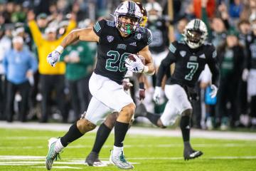 An OHIO football player runs with the ball in a game in Peden Stadium against Central Michigan University