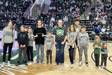 Participants of the Cat Camp diabetes day camp are shown posing for a photo on the basketball court at an OHIO Men's Basketball game